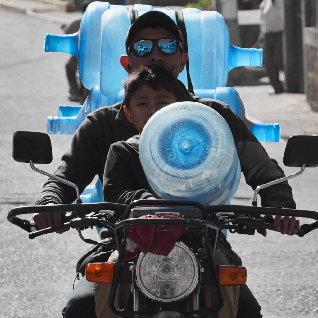 boy and father on moto with water jugs, Lake Atitlan, Guatemala