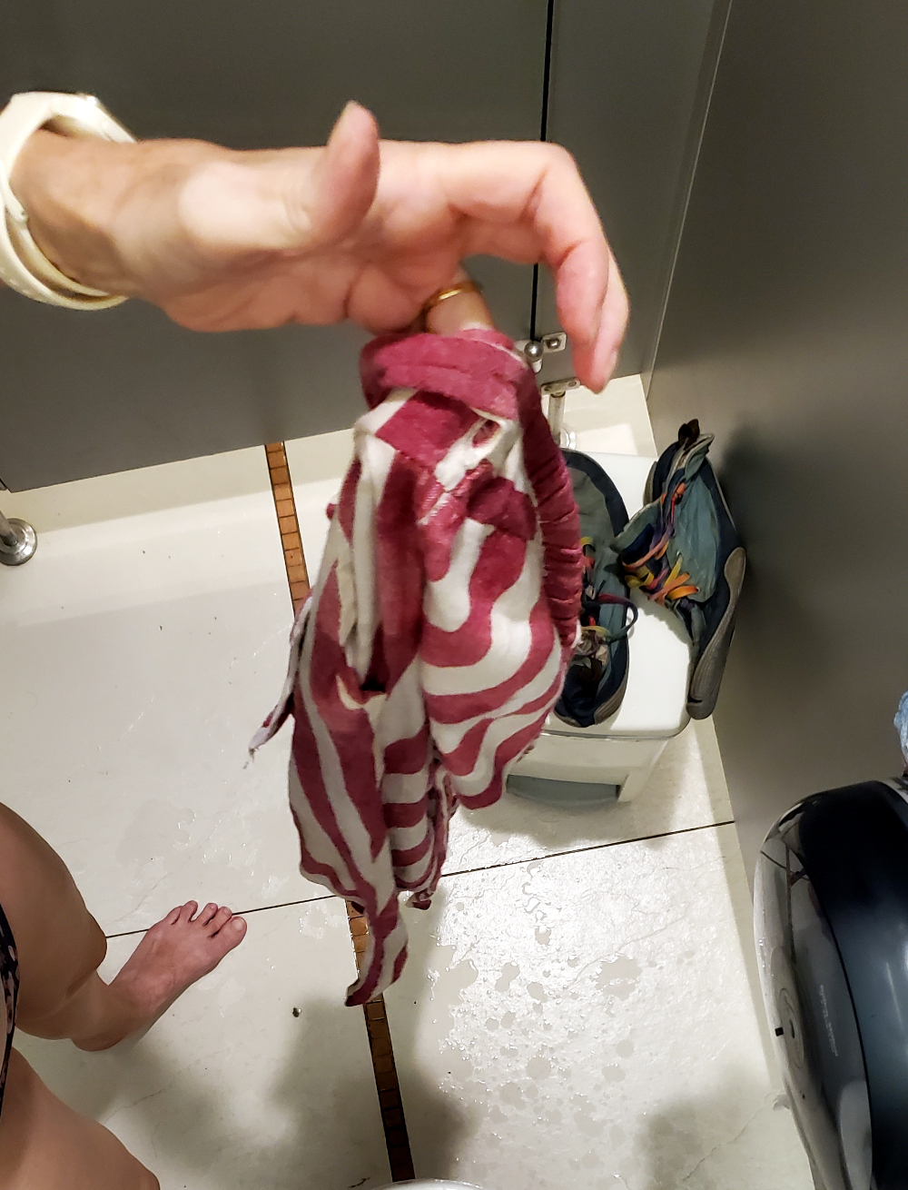unprepared for the rain, traveler's pants got soaked. wringing them out in a bathroom stall at the mall in Bangkok