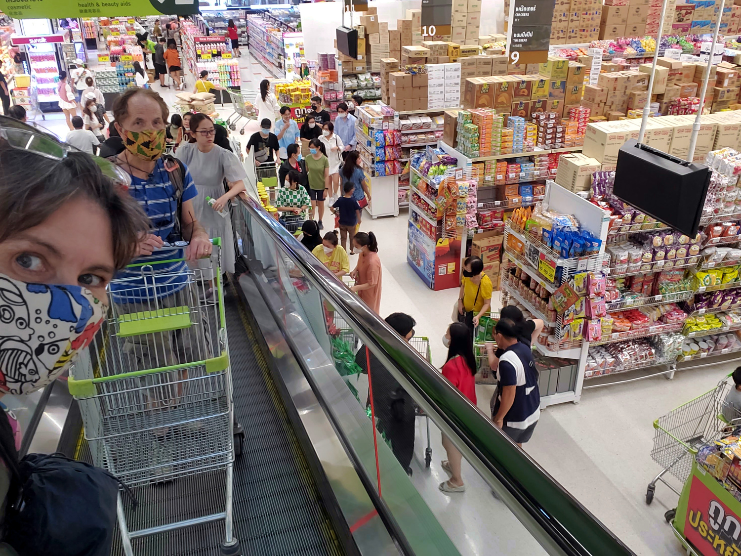 Frugal travelers shop like the locals. Taking the escalator with our shopping cart inside the supercenter.