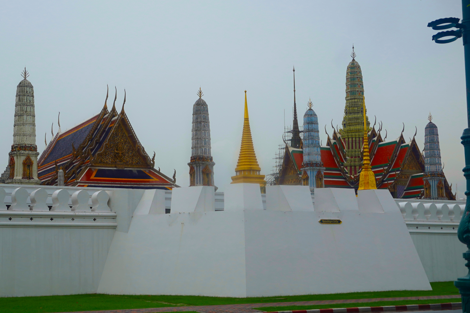 pillars on roof top of Wat behind white wall